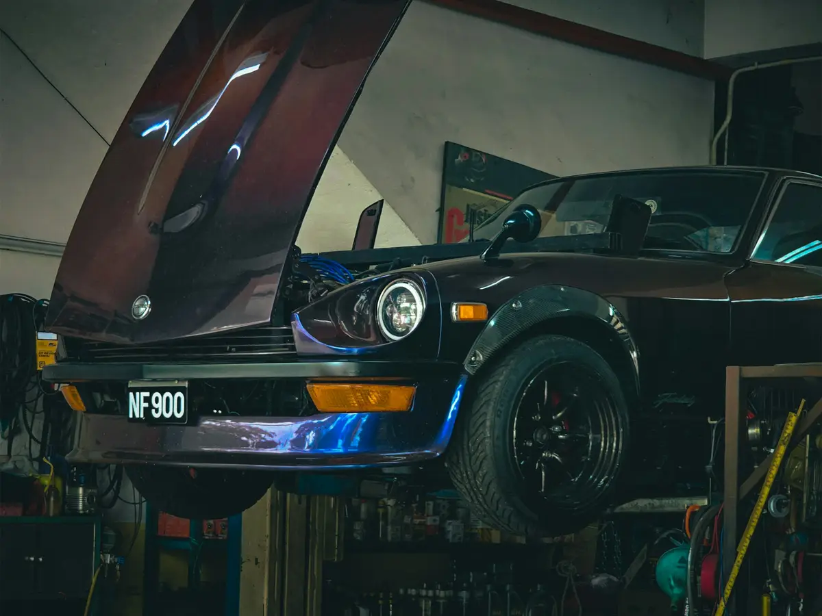 A car raised on a two-post ramp with the bonnet up