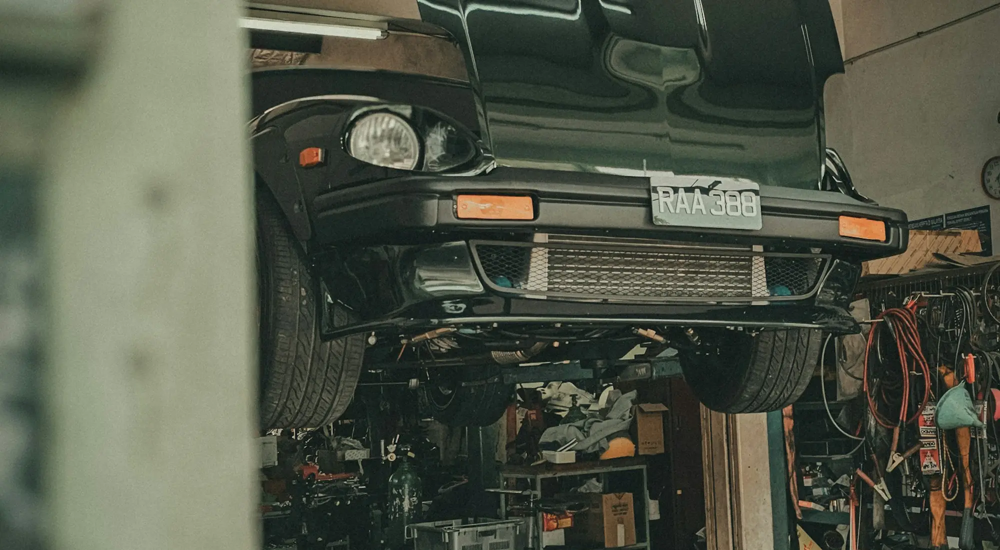 A car raised on a two-post ramp in the IRONWHEELMOTORS workshop