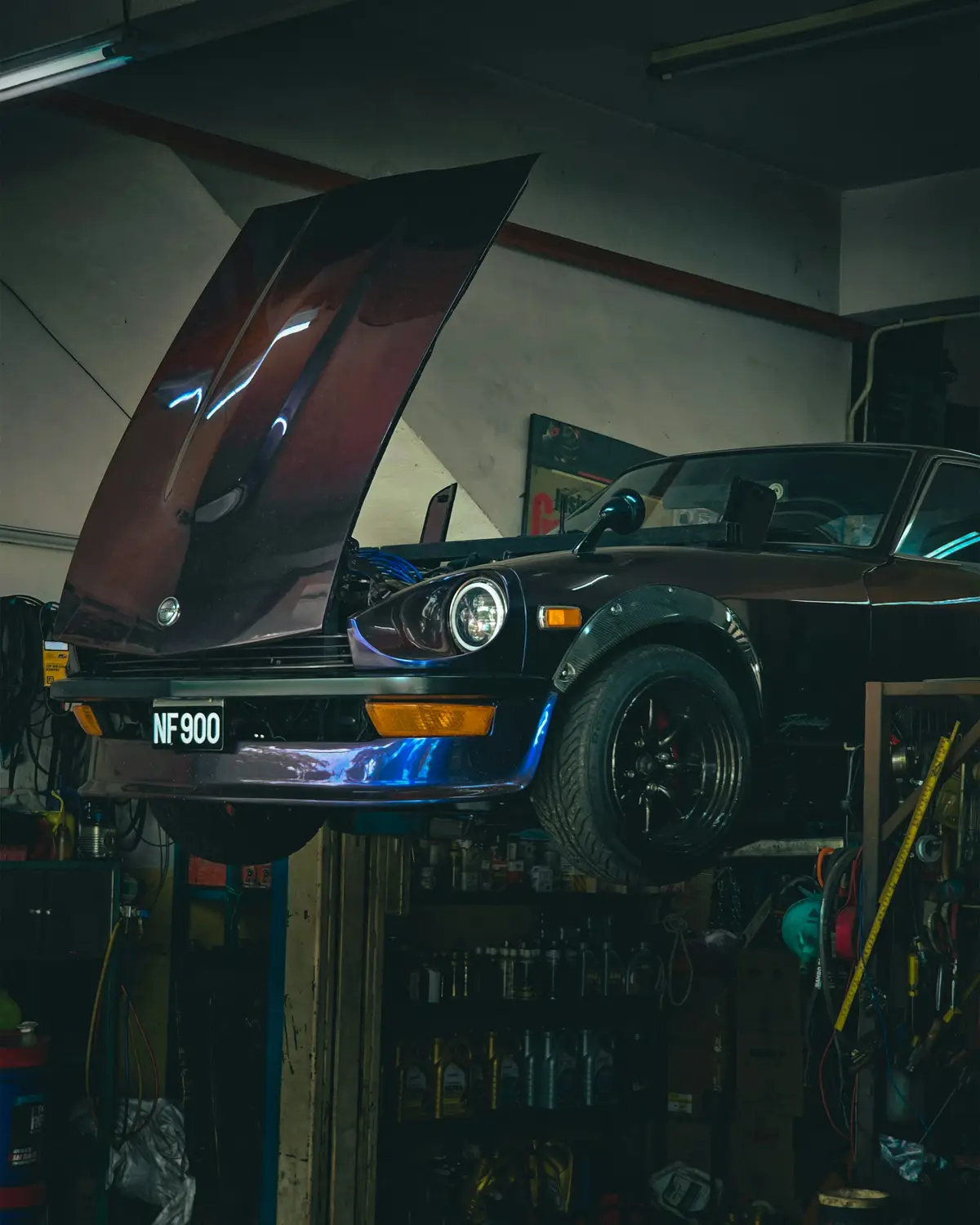 A car raised on a two-post ramp in the IRONWHEELMOTORS workshop